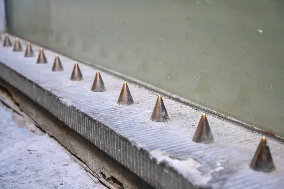 Spikes on building designed to prevent people from sitting.